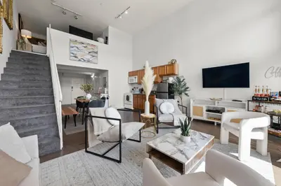a living room with white furniture and a staircase at The Italian Retreat, Little Italy in San Diego