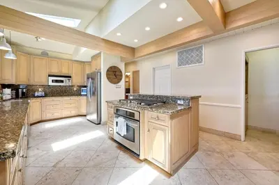 a large kitchen with wooden cabinets and stainless steel appliances at Villa Jules, Oceanfront, Private Beach, Fire Pit in Oceanside
