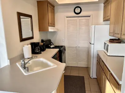a kitchen with a sink and a white refrigerator at Oceanfront 2BR Condo, Private Beach & Patio, Rare Find in Carlsbad