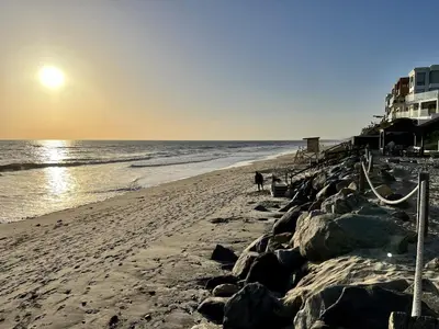 a person walking on a beach near the ocean at Oceanfront 2BR Condo, Private Beach & Patio, Rare Find in Carlsbad
