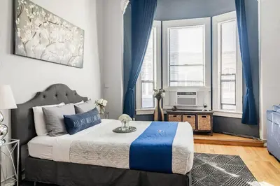 a bedroom with a bed with blue curtains and a television at Free Parking Loft Suite Walk to Conv Center in San Diego