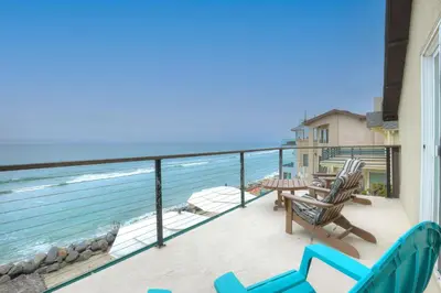 a balcony with chairs and a table and the ocean at Oceanfront 4BR, Private Beach & Patio, Remodeled Kitchen in Oceanside