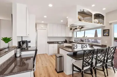 a kitchen with white cabinets and a island with chairs at California Dreamin Your Ocean-View Sanctuary in San Diego