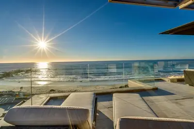 a room with a view of the beach and the sun at Luxury Beachfront Home with Hot Tub & Ocean Views in San Diego