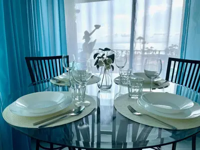 a glass table with plates and wine glasses on it at SurfView VR - Best Ocean and Pier View, 5 mins to Beach, Cozy Patio, Pet Friendly in San Clemente