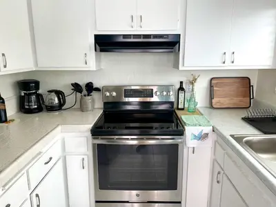 a kitchen with a stove and white cabinets at SurfView VR - Best Ocean and Pier View, 5 mins to Beach, Cozy Patio, Pet Friendly in San Clemente