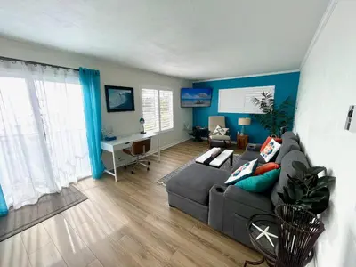 a living room with a gray couch and blue walls at SurfView VR - Best Ocean and Pier View, 5 mins to Beach, Cozy Patio, Pet Friendly in San Clemente