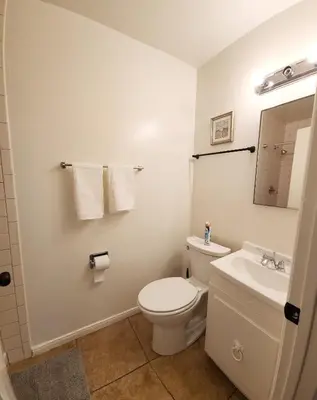 a white bathroom with a toilet and a sink at Centrally Located, 4x Queen, 300 MBPS Internet with Backyard! in Hemet