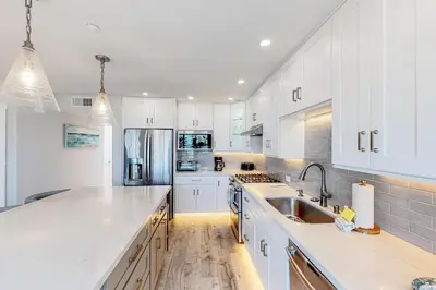 a kitchen with white cabinets and a stainless steel refrigerator at Pacific Sunset San Miguel 16 in Oceanside