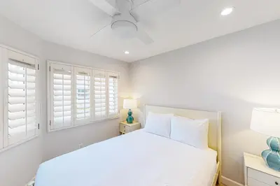a white bedroom with a bed and windows at Pacific Sunset San Miguel 16 in Oceanside