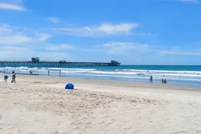 a group of people on a beach with a pier at Pacific Sunset San Miguel 16 in Oceanside