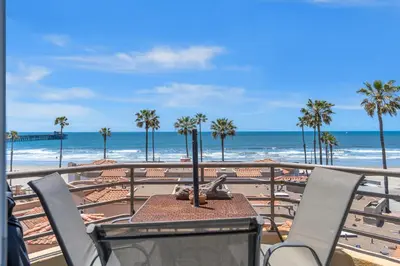 a table and chairs on a balcony overlooking the beach at Pacific Sunset San Miguel 16 in Oceanside