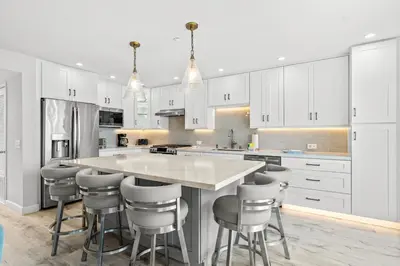 a kitchen with white cabinets and a large island with bar stools at Pacific Sunset San Miguel 16 in Oceanside