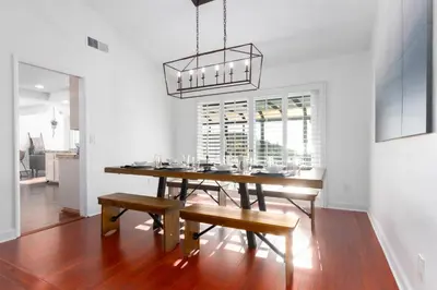 a dining room with a table and benches and a chandelier at Vacation Oasis! Ocean Views~Mini Golf~King-Suites in Solana Beach