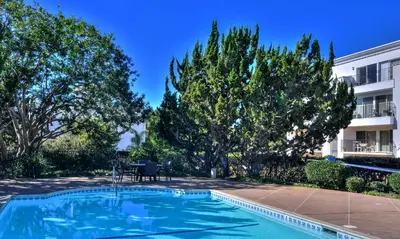 a swimming pool in a yard with trees and a building at 604 Gorgeous Renovated Condo, Steps to Omni Spa, Golf, Tennis, PFC & Exclusive Building Pool in Encinitas