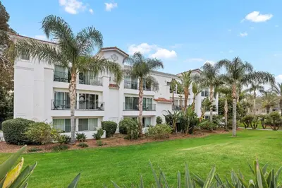 an apartment building with palm trees and a lawn at 604 Gorgeous Renovated Condo, Steps to Omni Spa, Golf, Tennis, PFC & Exclusive Building Pool in Encinitas