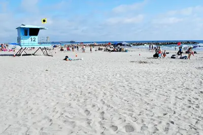 a group of people on a beach with a life guard tower at 207A Fresh, Renovated and Steps from the Beach in Oceanside