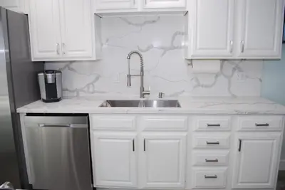a kitchen with white cabinets and a sink at 207A Fresh, Renovated and Steps from the Beach in Oceanside
