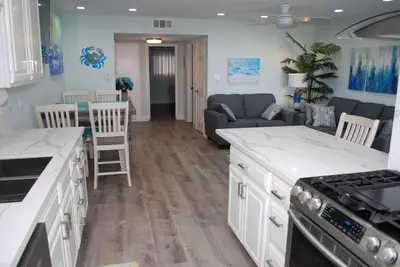 a kitchen with white cabinets and a living room at 207A Fresh, Renovated and Steps from the Beach in Oceanside