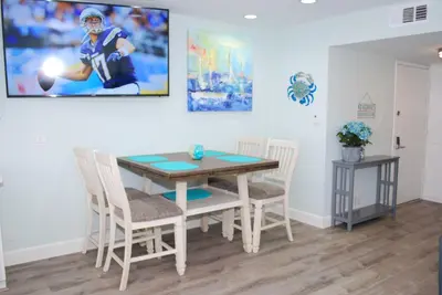 a dining room table and chairs with a football picture on the wall at 207A Fresh, Renovated and Steps from the Beach in Oceanside