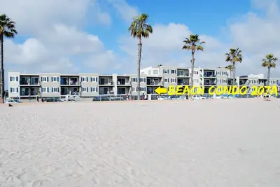 a building on the beach with palm trees in front of it at 207A Fresh, Renovated and Steps from the Beach in Oceanside
