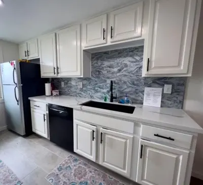 a kitchen with white cabinets and a black refrigerator at 209A Beach Living at its Best in Oceanside