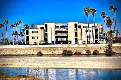 a large building next to a river with palm trees at 211A Freshly Renovated Steps from the Sand at the Beach Oceanside in Oceanside