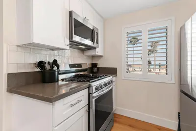 a white kitchen with a stove and a microwave at 211A Freshly Renovated Steps from the Sand at the Beach Oceanside in Oceanside