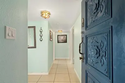 a hallway with a blue door and a tile floor at 211B - Harbor, Seals, Birds, Night Lights, Steps to the Sand! in Oceanside