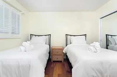 two twin beds in a room with white sheets at 212A Beachfront View-Free Wifi in Oceanside