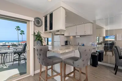 a kitchen with a island with bar chairs and a balcony at 215A - Beautiful Sunsets, Beach View, Free Wifi in Oceanside
