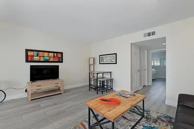 a living room with a television and a table at 303B Perfect Location Beach Across the Street - Walk to Shops Dining - Harbor Views in Oceanside