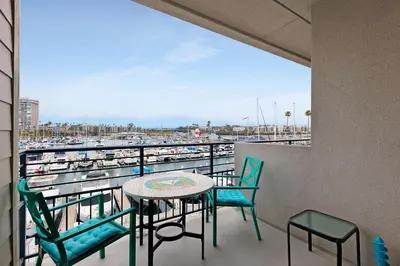 a balcony with a table and chairs and a harbor at 303B Perfect Location Beach Across the Street - Walk to Shops Dining - Harbor Views in Oceanside