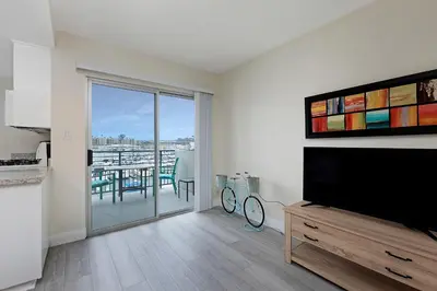 a living room with a television and a table with chairs at 303B Perfect Location Beach Across the Street - Walk to Shops Dining - Harbor Views in Oceanside