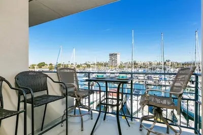 a balcony with chairs and tables and a view of a marina at 308B - Beautiful Harbor Ocean Retreat in Oceanside