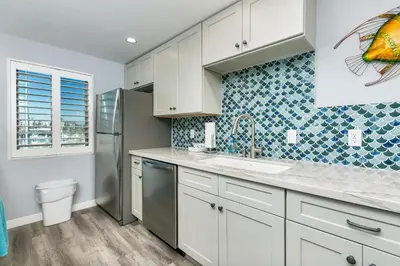 a kitchen with white cabinets and a sink and a refrigerator at 308B - Beautiful Harbor Ocean Retreat in Oceanside