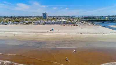 an aerial view of a beach with people in the water at 311B Harbor Views and Steps to the Sand in Oceanside