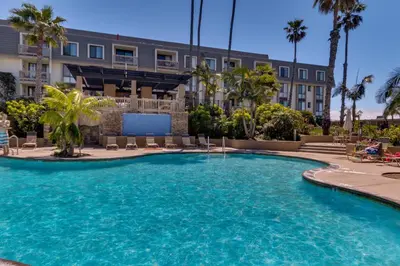 a pool in front of a building with palm trees at Tropical Water View at North Coast Village C200 in Oceanside