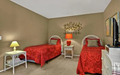 two beds in a room with red covers and a tv at Tropical Water View at North Coast Village C200 in Oceanside