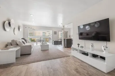 a white living room with a large flat screen tv at Beachfront Oasis - 30-Night Minimum in San Diego