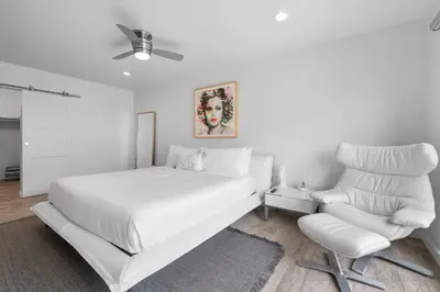 a white bedroom with a white bed and a white chair at Beachfront Oasis - 30-Night Minimum in San Diego