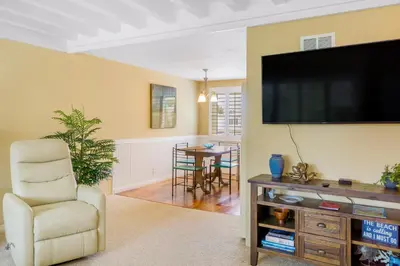 a living room with a tv and a chair and a table at Juniper Coastal Home - 30-Night Minimum in Carlsbad