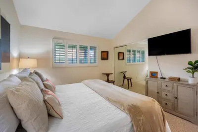 a bedroom with a large bed and a flat screen tv at Juniper Coastal Home - 30-Night Minimum in Carlsbad