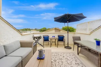 a patio with a couch and an umbrella at Juniper Coastal Home - 30-Night Minimum in Carlsbad