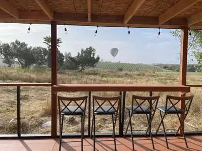a porch with four chairs and a hot air balloon in the distance at Modern wine country barn house in Temecula