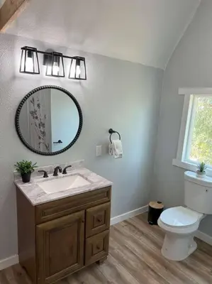 a bathroom with a sink and a toilet and a mirror at Modern wine country barn house in Temecula