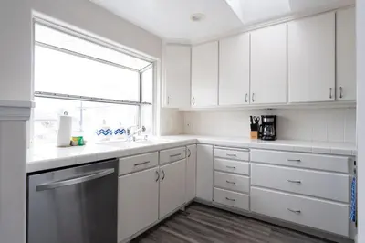 a white kitchen with white cabinets and a window at Sunlit La Jolla Village Gem with Peak Ocean Views in San Diego