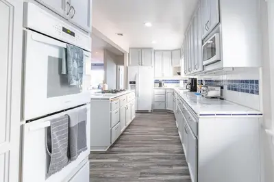 a white kitchen with white appliances and wooden floors at La Jolla Village's Premier Haven in San Diego