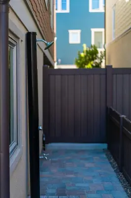 a black fence next to a house with a brick sidewalk at Pristine and Luxe, Steps to Mission Beach and Bay! in San Diego
