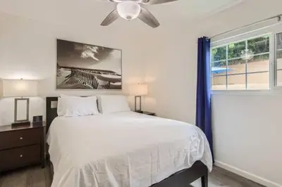a bedroom with a bed with a ceiling fan and a window at NEW - 6br home in Oceanside w Games BBQ Outdoor Seating in Oceanside